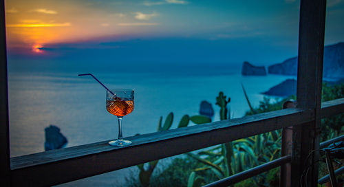 Close-up of drink on railing against sea