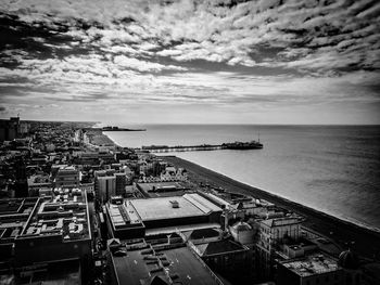 Brighton pier on sea against cloudy sky in city