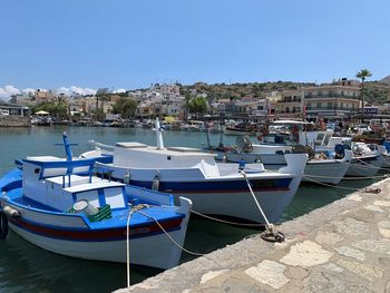 Sailboats moored on sea by buildings against clear blue sky