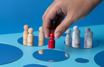 Cropped hand of person playing with pills against blue background