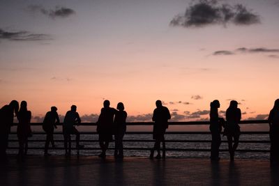 Silhouette people at beach against sky during sunset