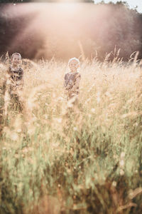 Portrait of smiling siblings standing amidst plants on field