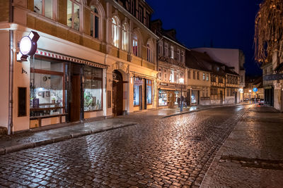 Illuminated street amidst buildings at night