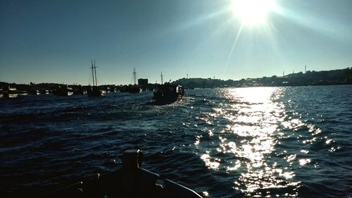 Silhouette boat sailing in sea against clear sky on sunny day