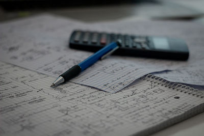 High angle view of book with calculator and pen on table