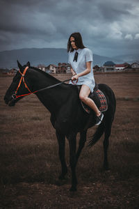 Woman and horse against cloudy sky