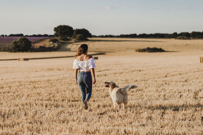 Mid adult woman with dog on agricultural field