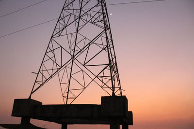 Low angle view of silhouette electricity pylon against sky at sunset