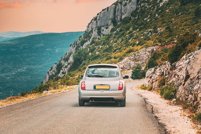 Car on road by mountains against sky