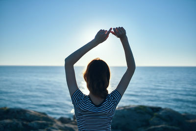 Rear view of woman standing in sea against clear sky