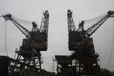 Low angle view of crane at construction site against sky