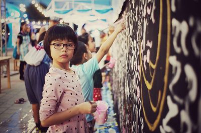 Portrait of cute girl painting wall outdoors