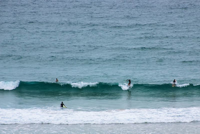 People surfing on wave in sea