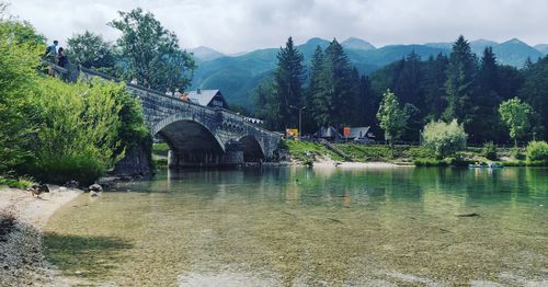 Arch bridge over river against cloudy sky