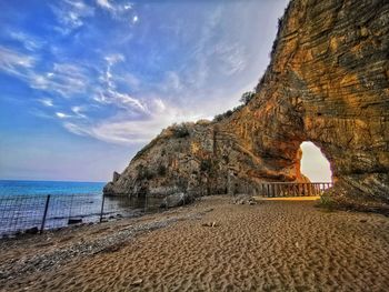 Rock formation on beach against sky