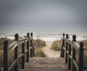 Boardwalk leading towards beach against sky