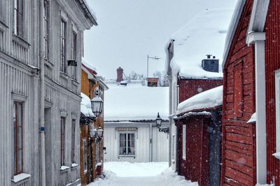 Snow covered houses amidst buildings in city