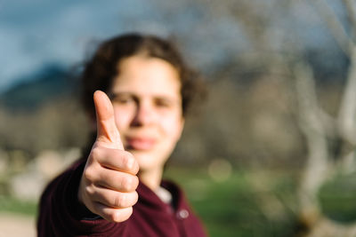 Portrait of teenage girl showing thumbs up sign