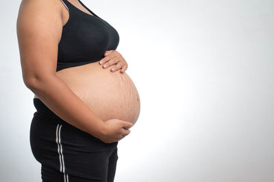 Midsection of woman touching face against white background