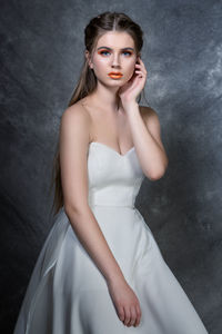 Portrait of beautiful young woman wearing make-up against wall