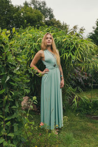 Portrait of young woman standing against plants