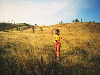 Full length of woman walking on field against sky