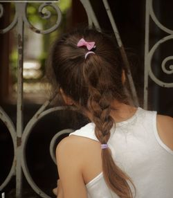 Rear view of curious girl looking through metal fence