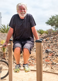 Smiling man balancing on railing against sky