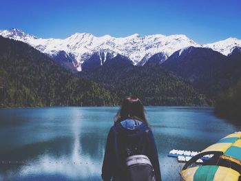 Rear view of woman looking at snowcapped mountains and lake against sky