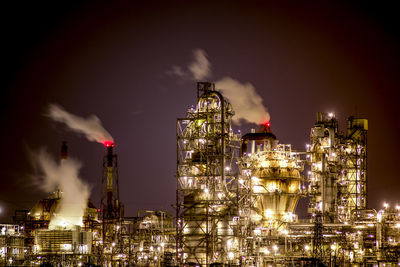 Low angle view of illuminated industry against sky at night