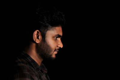 Profile view of young man against black background