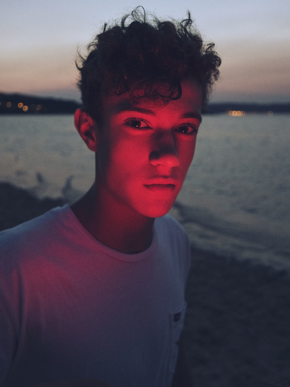 beach, portrait, water, sea, one person, land, young adult, focus on foreground, headshot, young men, sunset, leisure activity, real people, front view, nature, looking at camera, lifestyles, casual clothing, outdoors, contemplation, teenager