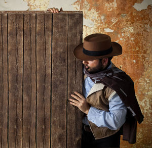 Man wearing hat standing against wall