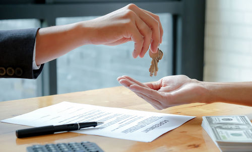 Cropped image of hand holding paper on table