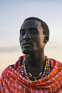 Portrait of young man looking away against sky