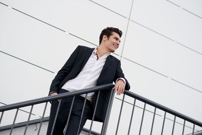 Low angle view of businessman standing by railing against wall