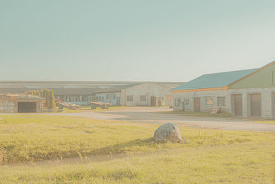 Field by buildings against clear sky