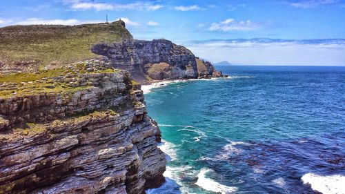 Scenic view of sea by cliff against sky