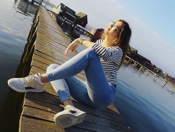 Woman sitting on pier against lake