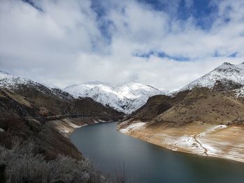 Scenic view of lake by snowcapped mountains against sky