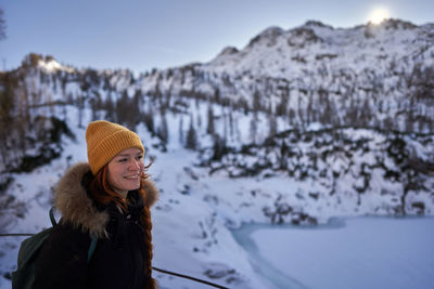 Portrait of smiling young woman standing on snow covered field