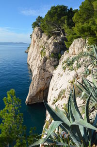 Rock formation by sea against sky