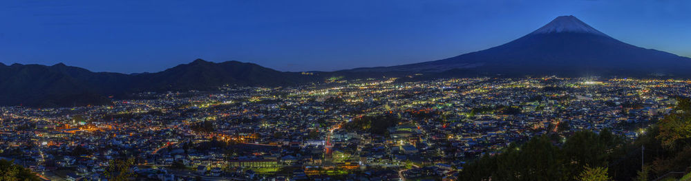 Aerial view of illuminated cityscape against blue sky