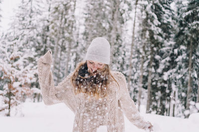 Woman wearing hat against trees in forest during winter