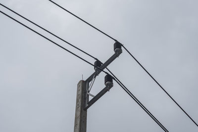 Low angle view of bird perching on cable against sky