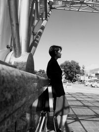 Side view of woman smoking cigarette while leaning on railing