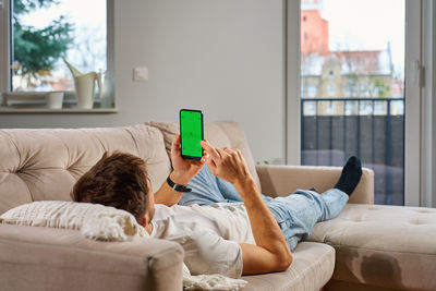 Woman using mobile phone while sitting on bed at home
