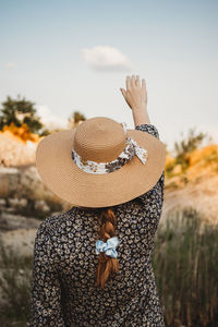 Woman with hat touching the clouds