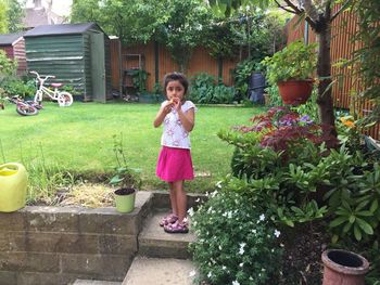 Portrait of young woman standing in yard