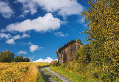 Dirt road amidst buildings against sky